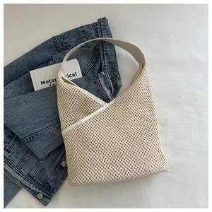 Détail du sac seau tissé crème avec texture ajourée complexe et bandoulière lisse élégante