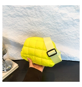 Détail d'un sac bandoulière matelassé jaune avec texture bouffante et sangle tissée