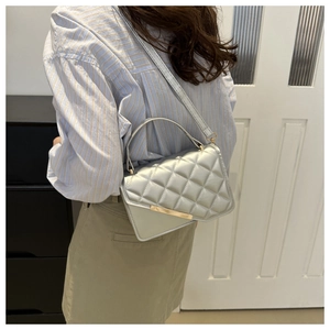 Detail of silver-grey quilted crossbody bag with gold metal buckle and slender shoulder strap
