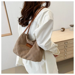 Detail of brown checkered embossed shoulder bag with leather logo patch on white shirt