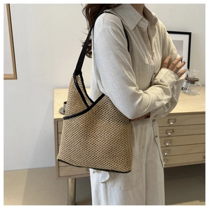 Detail of hand-woven straw tote with black leather trim and mesh texture on model