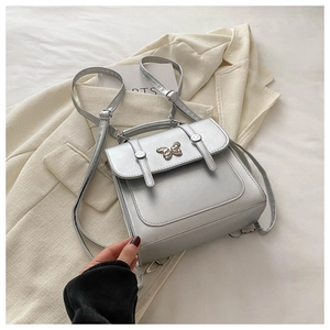 Detail of silver faux leather backpack featuring a decorative metal butterfly clasp and handle