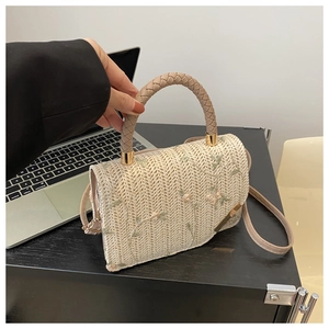 Detailed view of bohemian straw handbag with flower embroidery and metal hardware