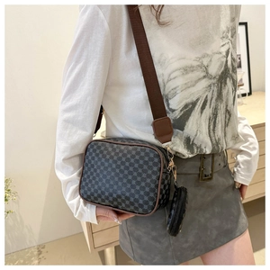 Detail of grey crossbody camera bag with geometric pattern and wide brown strap