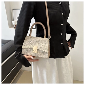 Detail of woven straw handbag featuring delicate floral embroidery and metal twist lock