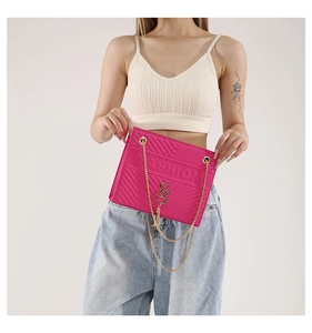 Detail of hot pink quilted chain bag with gold logo and tassel on a female model