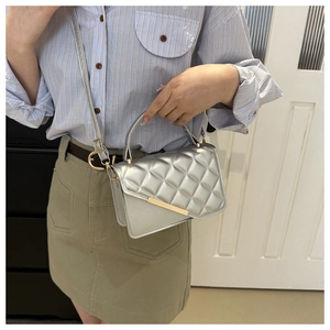 Silver quilted crossbody bag with gold hardware and adjustable strap shown on model