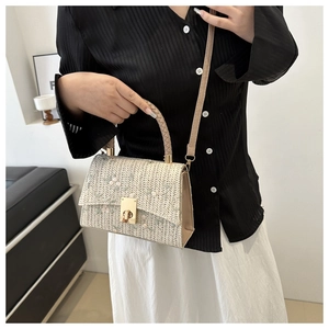 Close-up of floral embroidery on off-white straw woven bag with gold metal lock buckle