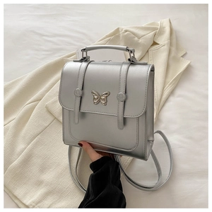 Detail of silver metallic butterfly buckle on a textured PU leather mini backpack