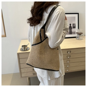 Detail of handmade straw bucket bag with black leather trim and shoulder strap