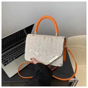 Close-up of woven straw handbag with floral embroidery and orange braided handle