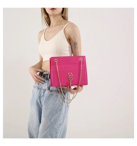Detail of fuchsia V-quilted crossbody bag with gold SS logo and chain strap detail