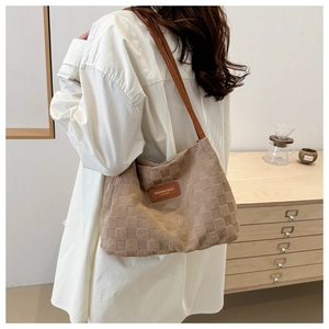 Detail of khaki tote bag with checkerboard texture and brown leather logo patch