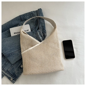 Détail du sac seau tissé blanc cassé montrant la texture maille et la large bandoulière