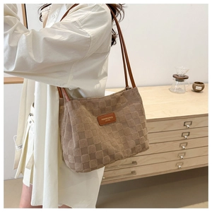 Detailed close-up of brown checkered plush tote bag with fashion leather tag detail