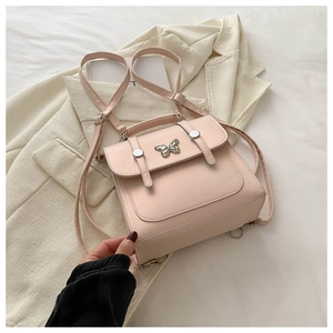 Detailed view of pink PU leather backpack with silver butterfly clasp on a beige blazer