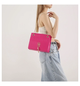 Detail of rose red quilted crossbody bag with golden chain strap and fringe charm