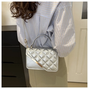 Silver quilted crossbody bag with diamond texture and metallic finish on model back