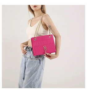 Detail of rose pink crossbody bag with V-shaped quilting and golden tassel chain strap
