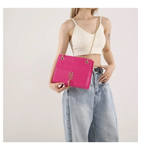 Detail of rose red quilted crossbody bag with gold chain strap and tassel charm