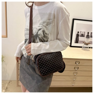 Close-up of retro printed crossbody bag with brown leather trim and wide strap