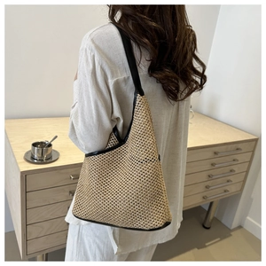 Detail of hand-woven straw shoulder bag with black leather straps and mesh texture