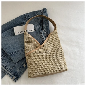 Détail d'un sac seau tissé beige avec poignée en cuir sur fond minimaliste épuré