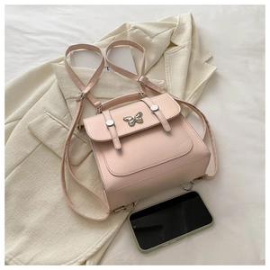 Detail view of pink PU leather mini backpack with silver butterfly buckle on a blazer