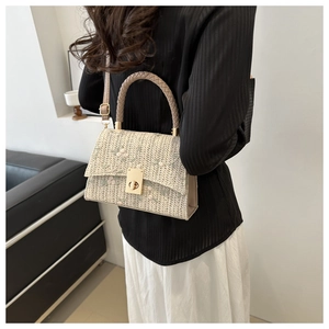 Detail of straw woven bag with floral embroidery and gold twist lock closure