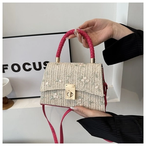Detailed embroidery floral pattern on cream woven handbag with vibrant pink handle and gold lock