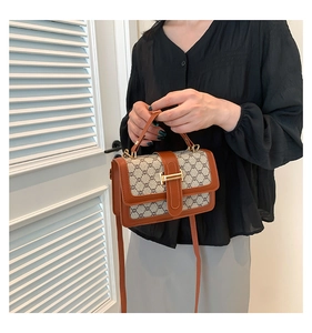 Détail d'un sac à bandoulière vintage monogrammé avec fermoir doré et cuir brun