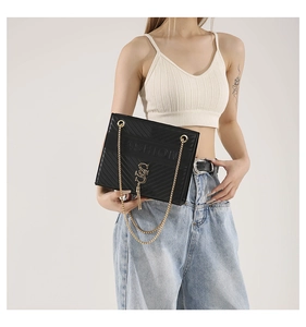 Detail of black quilted leather shoulder bag with gold chain strap and fringe tassel