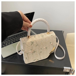 Detail of floral embroidery on a hand-woven small square bag with braided handle