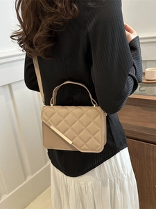 Chic beige quilted crossbody bag with gold metal trim shown on a model in a cafe