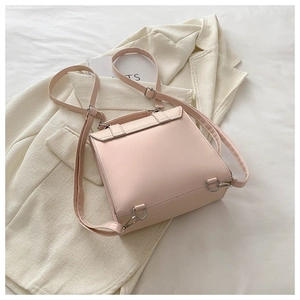 Close-up of pink faux leather bag with adjustable silver buckles on light blazer background