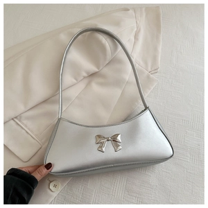 Detail of silver metallic underarm bag with a decorative bow knot and sleek finish