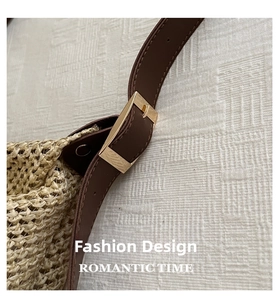 Detail of adjustable dark brown strap with gold buckle on beige woven tote bag