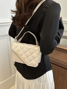 White quilted crossbody bag with gold metal trim and single handle shown on model