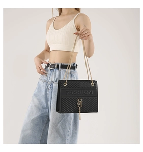 Detail of black quilted shoulder bag with golden tassel metal buckle and fashion logo