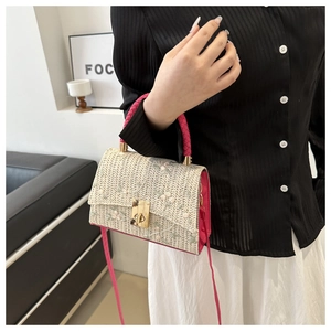 Detail of floral embroidery on straw crossbody bag with rose red woven accents
