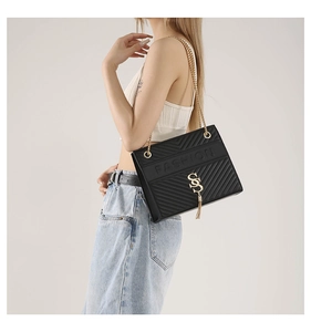 Detail view of black quilted crossbody bag featuring gold chain and tassel hardware
