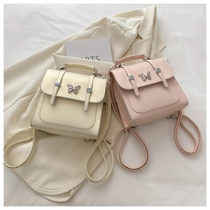 Detail view of cream and pink square flap bags with silver butterfly and buckled straps