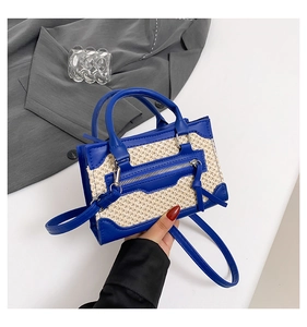 Détail du mini sac en paille avec bordure en cuir bleu et pompon sur fond blanc