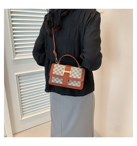Detail of vintage crossbody bag with grey monogram pattern and brown leather trim