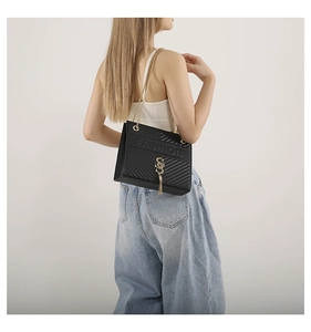 Detail of black V-quilted shoulder bag with gold chain and FASHION embossed text