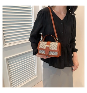 Detail of vintage patterned crossbody bag with brown leather trim and golden H buckle