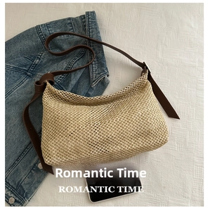 Detail of hand-woven straw tote with leather straps next to a smartphone for size scale