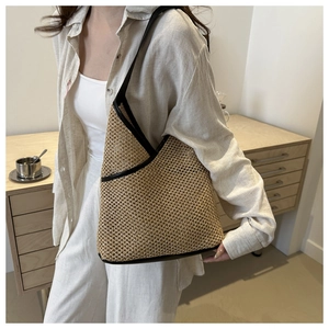 Detail of handmade straw woven tote bag featuring black leather trim and mesh texture