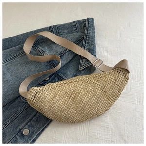Détail d'un sac ceinture en paille tressée avec bandoulière beige sur denim
