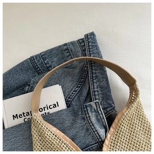 Détail d'un sac seau en paille avec bordure en cuir marron sur fond en jean